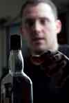 A Twelve Step group member reaches for his bottol of alcohol