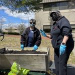 Two People Planting Outdoors With Masks On