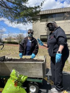 Two People Planting Outdoors With Masks On