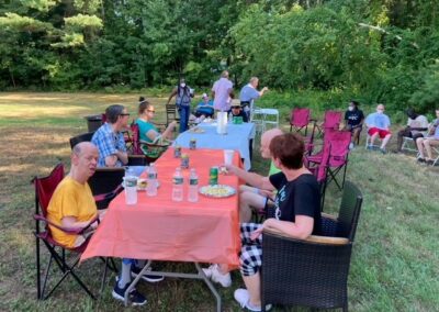 Summer BBQ People Sitting At Tables Eating