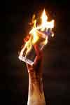 THe burnt hand of an internet sex addict holds a cell phone on fire